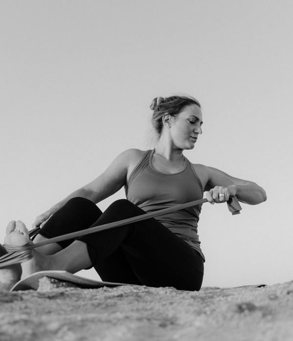 Person demonstrating a flexibility-focused yoga pose outdoors at sunset.