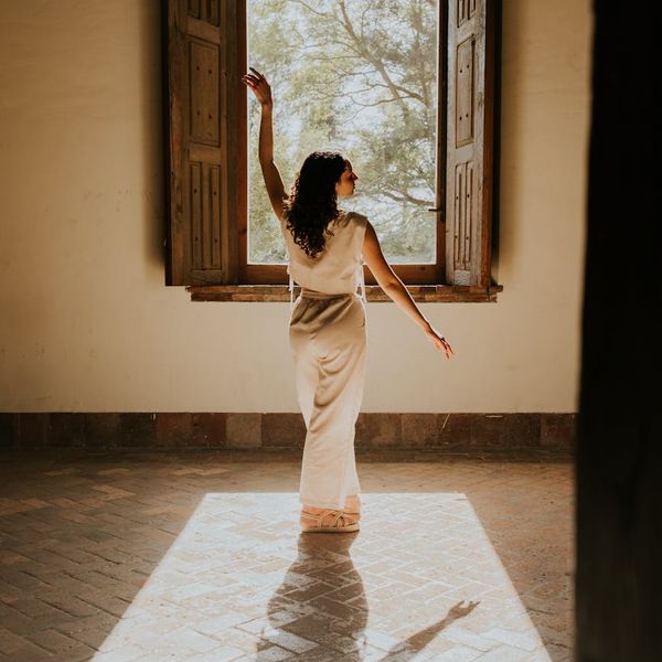 Woman in a calm, seated meditative pose in a softly lit room.